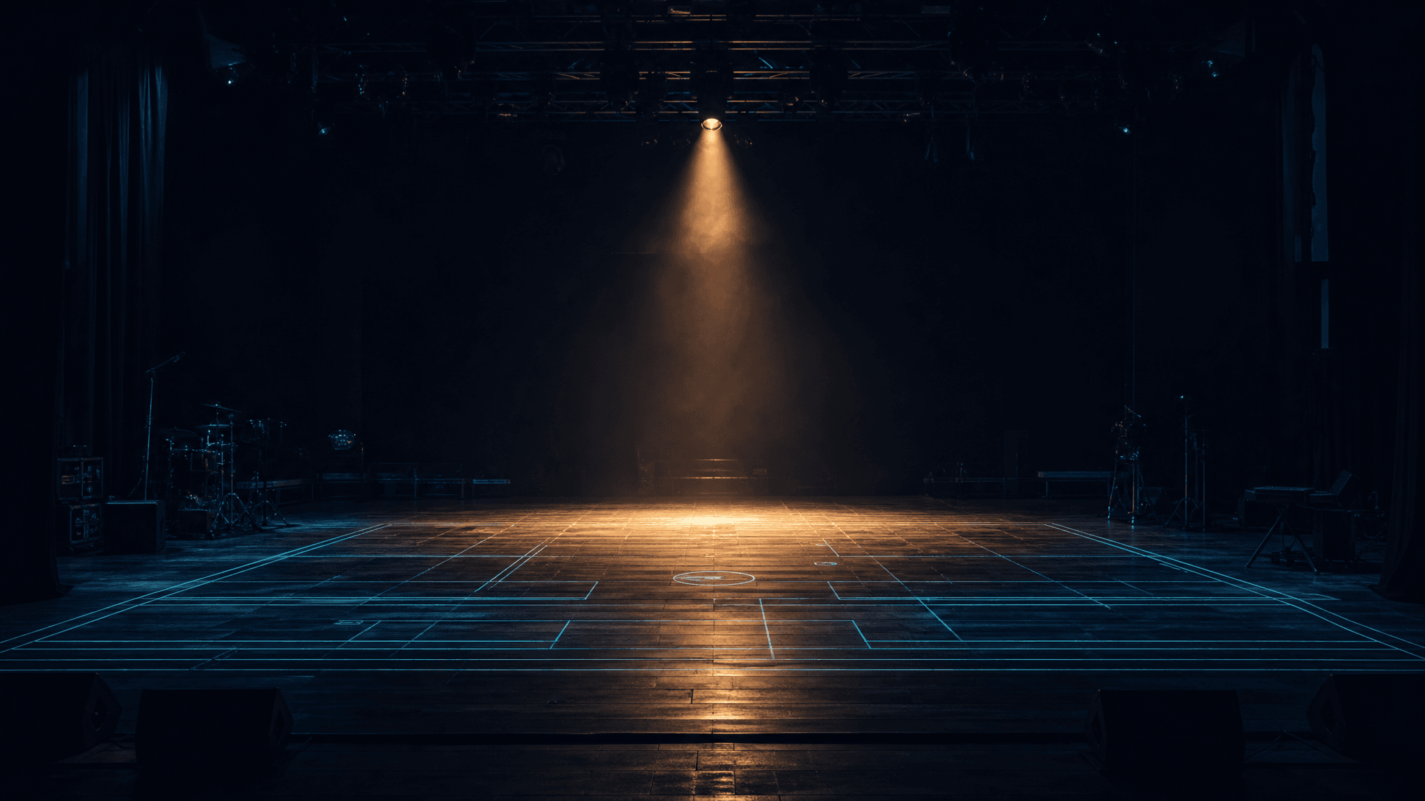 Empty stage lit by a single amber spotlight with a cyan stage-plot wireframe on the floor
